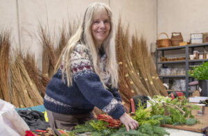 Grøne fingrar: Marit Byberg er i full sving i verkstaden. Juletregarden på Voll har vore i drift i snart tjue år. Interessa for gravlegg, dørkransar og piletreprodukt er stor, og mange deltek på kurs for å læra teknikkane sjølv.