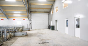 Effektiv fôring: Fôrgangen går på tvers gjennom huset. Her køyrer bonden med same fullfôrvogna som i kufjøset. Vogna matar blandinga på dei tre 50 meter lange rullande fôrbretta. Serviceavdeling, lager og kontor m.m. til høgre.