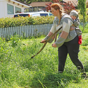 Tidleg trening: Berit Kathrine med vesle Tobias på ryggen. Kan tru han blir god med ljå etter nokre år, treninga byrja i alle fall tidleg.